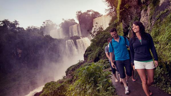 girl walking with group on a path below the beautiful Iguassu falls in Argentina